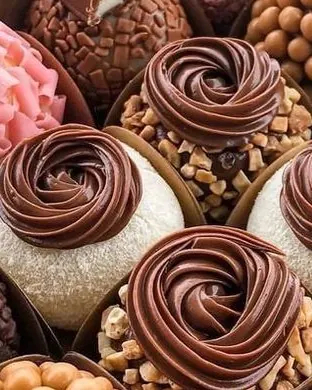 Brigadeiros gourmet com rosetas de chocolate e castanhas, lado a lado em forminhas